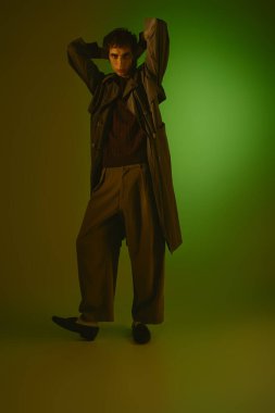 Stylish young man confidently poses in a colorful studio setting.