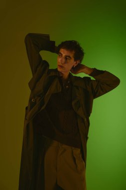 Handsome young man poses gracefully in a fashionable outfit, showcasing his unique style.