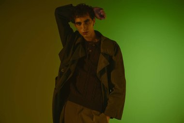 Stylish young man posing against a bold green background.