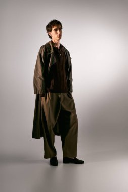 Handsome young man showcases unique style with elegant attire in a minimalist setting