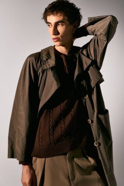 A handsome young man poses confidently, dressed elegantly in trendy attire, capturing attention.