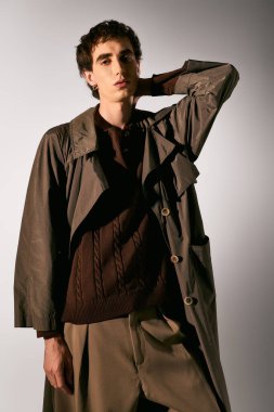Handsome young man poses elegantly in trendy attire, showcasing his fashion sense with ease.