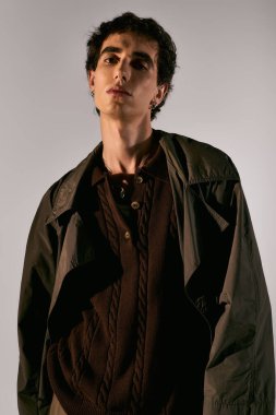 Handsome young man stands confidently in trendy attire against a simple background, exuding charm.