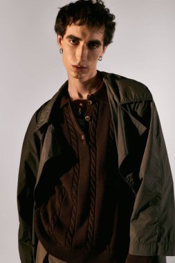 A handsome young man stands confidently, showcasing his trendy outfit against a neutral backdrop.