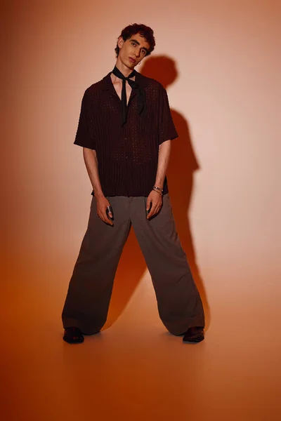 Young man showcases trendy attire with a bold pose, radiating charm and creativity. — Stockfoto