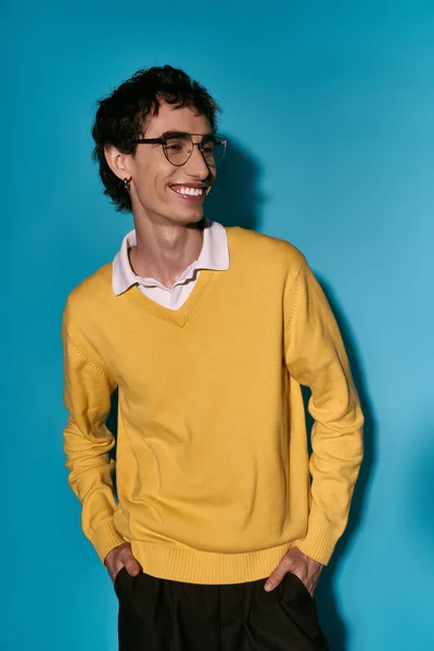 Handsome young man in a bright sweater stands confidently, radiating joy and style. - foto de stock