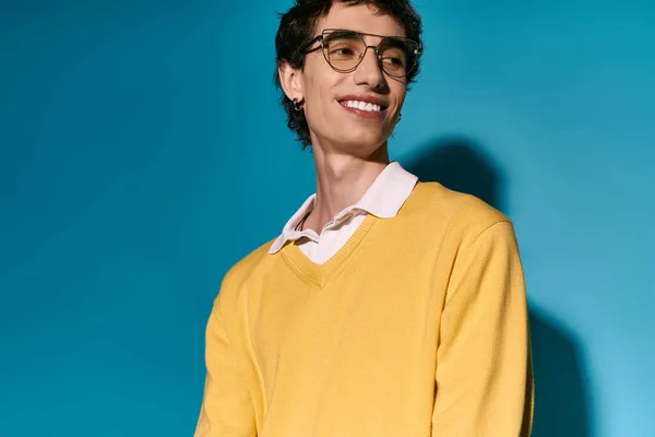A handsome young man smiles confidently, dressed in a trendy yellow sweater with a white collar. — Stock Photo