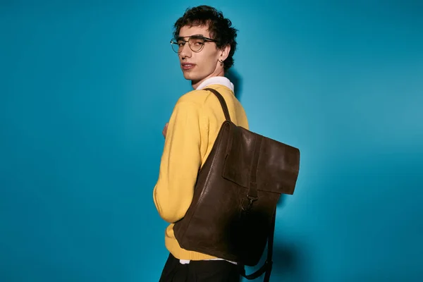Young man in fashionable attire poses confidently, highlighting his trendy backpack and style. — Fotografia de Stock