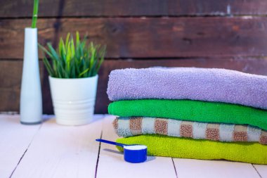 Ahşap arka planda katlanmış temiz renkli havlular. Evde çamaşırhane var.