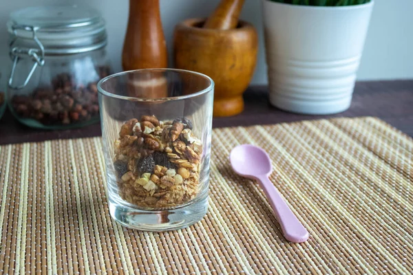 Useful muesli with nuts in a glass and a spoon on a wooden table. Healthy lifestyle — Stock Photo, Image
