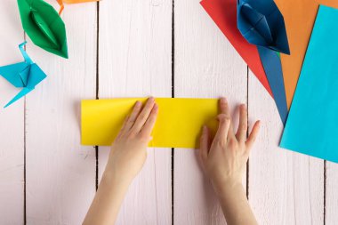 Bir kız origami yapmak için kağıt katlar. Kendin yap.