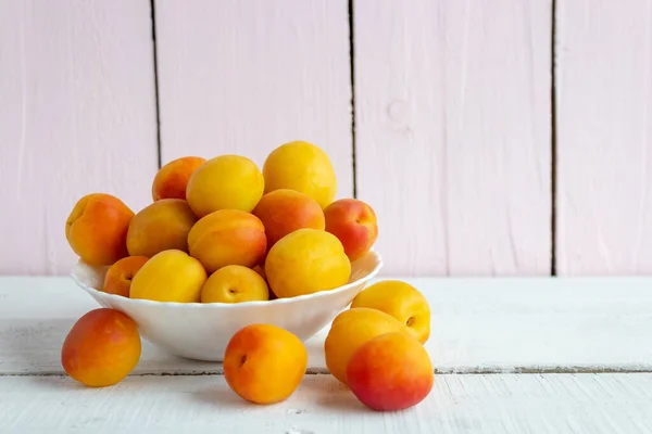 Fresh apricots on a plate on a wooden background. Summer harvest — Stock Photo, Image