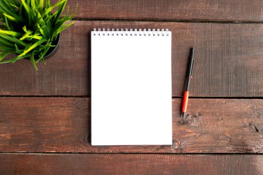 Çalışma ortamı. Mesaj, kalem, saat, telefon için yeri olan boş bir Not Defteri. Ahşap bir arka planda, üst manzara