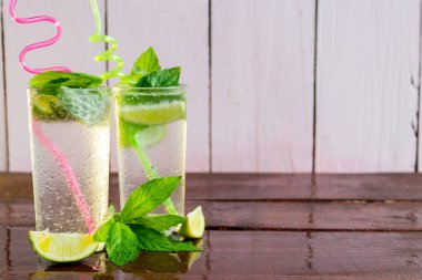 Ahşap arka planda iki bardak tazeleyici Mojito. Sıcağa karşı yaz içkileri