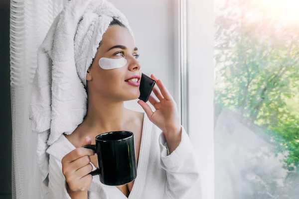 Beyaz Havluyla Bornozlu Kahve Içen Evdeki Pencerenin Yanında Telefonla Konuşan — Stok fotoğraf