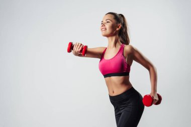 Dambıllarla Egzersiz Yapan Kız Gri Arkaplan Üzerinde Kameranın Önünde Duruyor