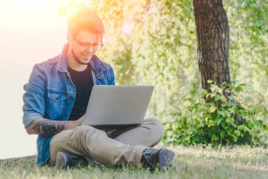 Dışarıda dizüstü bilgisayarda çalışan yakışıklı bir serbest yazar. Açık hava iş kavramı.