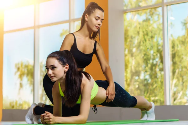 Genç beyaz kadın spor salonundaki antrenörüyle kalas yapıyor. Sağlıklı yaşam tarzı kavramı