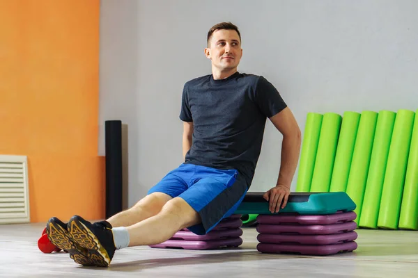 Genç beyaz adam fitness stüdyosundaki bir platformda şınav çekiyor. Sağlıklı yaşam tarzı kavramı. 