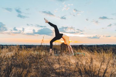 Genç kız gün batımında dışarıda yoga yapıyor.. 