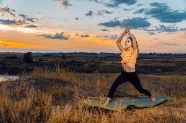 Genç kız gün batımında dışarıda yoga yapıyor.. 