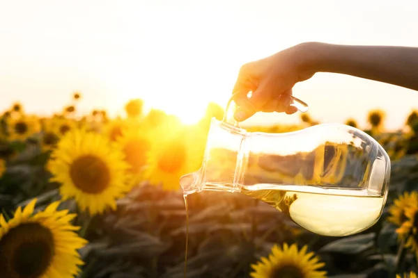 Gießen Sonnenblumenöl Aus Krug Auf Sonnenblumenfeld Hintergrund — Stockfoto