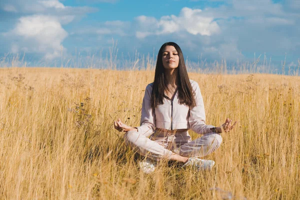 Sarı tarlada yoga yapan hoş bir kadın. Bakım kavramı
