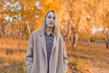 Sonbahar ormanında uzun paltolu güzel bir kadın. Sonbahar konsepti.