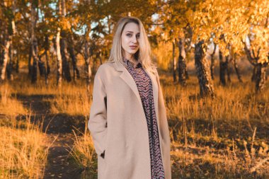 Sonbahar ormanında uzun paltolu güzel bir kadın. Sonbahar konsepti.