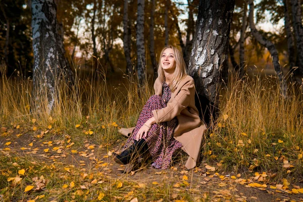 Молодая Красивая Улыбающаяся Женщина Длинном Пальто Сидит Земле Осеннем Лесу — стоковое фото