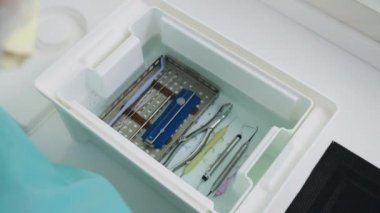 Diş hekiminin elleri, diş şırıngasını sterilize eden alkol sıvısına batırır.