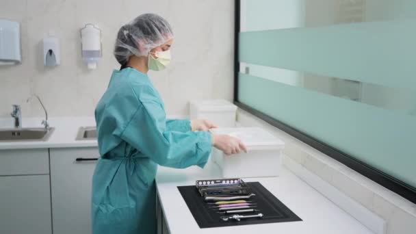 Une technicienne en clinique dentaire met des instruments dans une solution désinfectante — Video