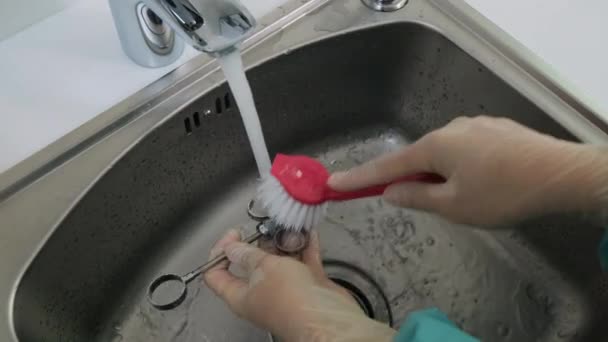 Sluiten van handen in handschoenen wassen tandheelkundige medische instrumenten onder een stromend water — Stockvideo