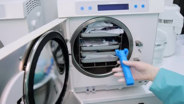 Dentiste prend des paquets avec des outils dentaires de l'autoclave. Prise de vue grand angle — Video