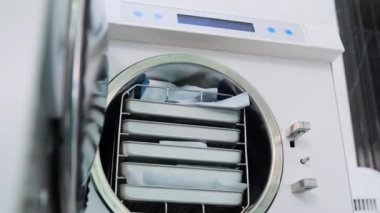Teknisyen ambalajı otoklavdan alıyor. Tıbbi fırının düşük açılı görüntüsü.