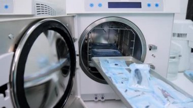 Laboratuvar teknisyeni otomatik klavuzu sterilizasyon için paket diş aletleriyle doldurdu