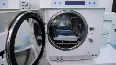 Teknisyen, sterilizasyondan sonra otomatik klavuzu diş aletleriyle hızlıca boşalttı