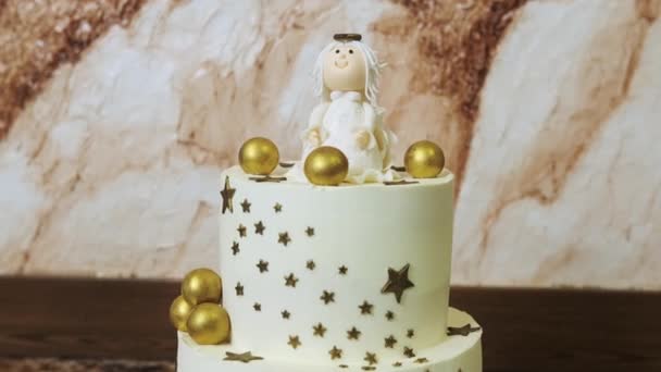 Um saboroso bolo branco decorado com estrelas douradas e bolas com figura de um anjo — Vídeo de Stock