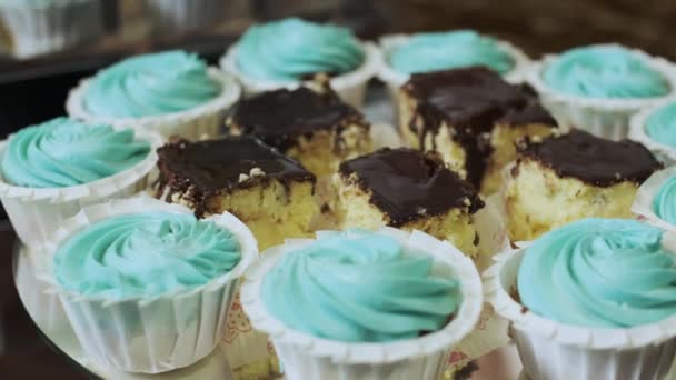 Close-up de cupcakes turquesa e cheesecakes com chocolate em uma barra de doces — Vídeo de Stock