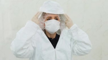 Beyaz koruyucu maskeli doktor kaputu çeker ve fermuarını çeker.