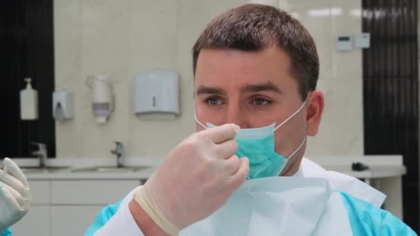 De patiënt zet een beschermend masker op na medische tandheelkundige ingrepen — Stockvideo