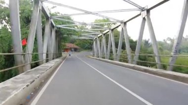 Motosiklet otoyoldaki demir köprüden geçiyor.