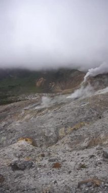 Garut, Endonezya 'da bulutlu gökyüzünün altında kızgın sülfür delikleriyle Papandayan Dağı' nın dramatik manzarası.