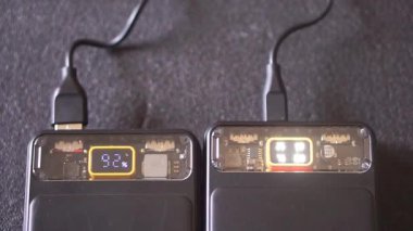 LED dijital ekranlı iki siyah güç bankası şarj olurken pil kapasitesini gösteriyor