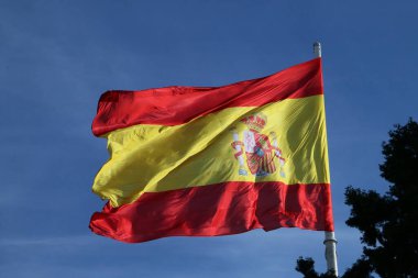 Kolon Meydanı, Madrid, İspanya 'da büyük bir İspanyol bayrağı. Rüzgarlı bir günde mavi gökyüzü.