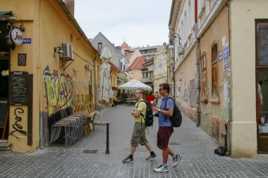 Brasov / Romanya; 06 / 26 / 2018. Cumhuriyet Caddesi, Rumence: strada republicii, Brasov 'un tarihi merkezinde. İki genç turist, bir yaz öğleden sonra, orta teraslı caddede geziniyorlar..