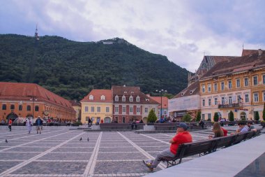 Brasov / Romanya; 06 / 26 / 2018. Brasov 'un Piata sfatului (Council Square). Konsey meydanında tepe ve üzerinde Brasov posteri olan binaların üzerinde duruyordu..