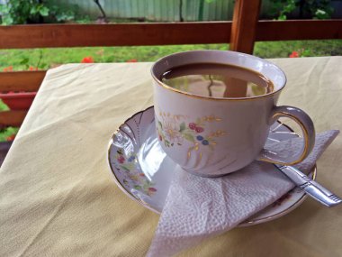 Geleneksel Romanya bardağında sütlü kahve. Romanya 'nın Curtea de Arges kentinde açık havada kahvaltı.