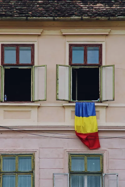 Romanian flag hanging from a window. Facade of a building in the downtown of Sighisoara, Romania.