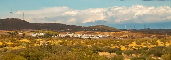 El Granado, a small town of whitewashed houses in the southwest of Spain. Town located in a valley surrounded by hills. El Sardon wind farm in the background over the area of the same name.